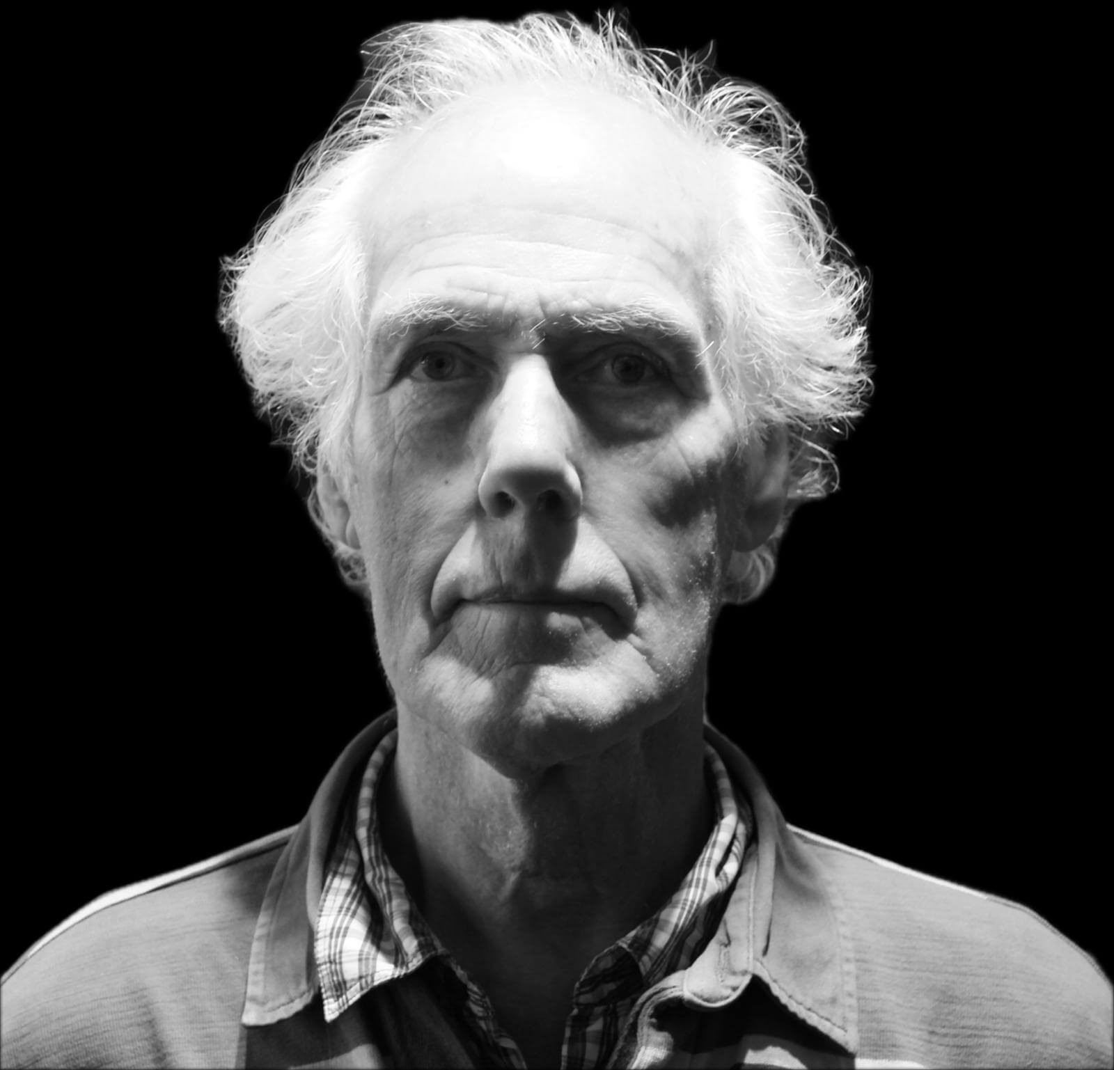 Portretfoto van Dirk, een levendige man van 70 jaar, die recht in de camera kijkt met een vastberaden blik.