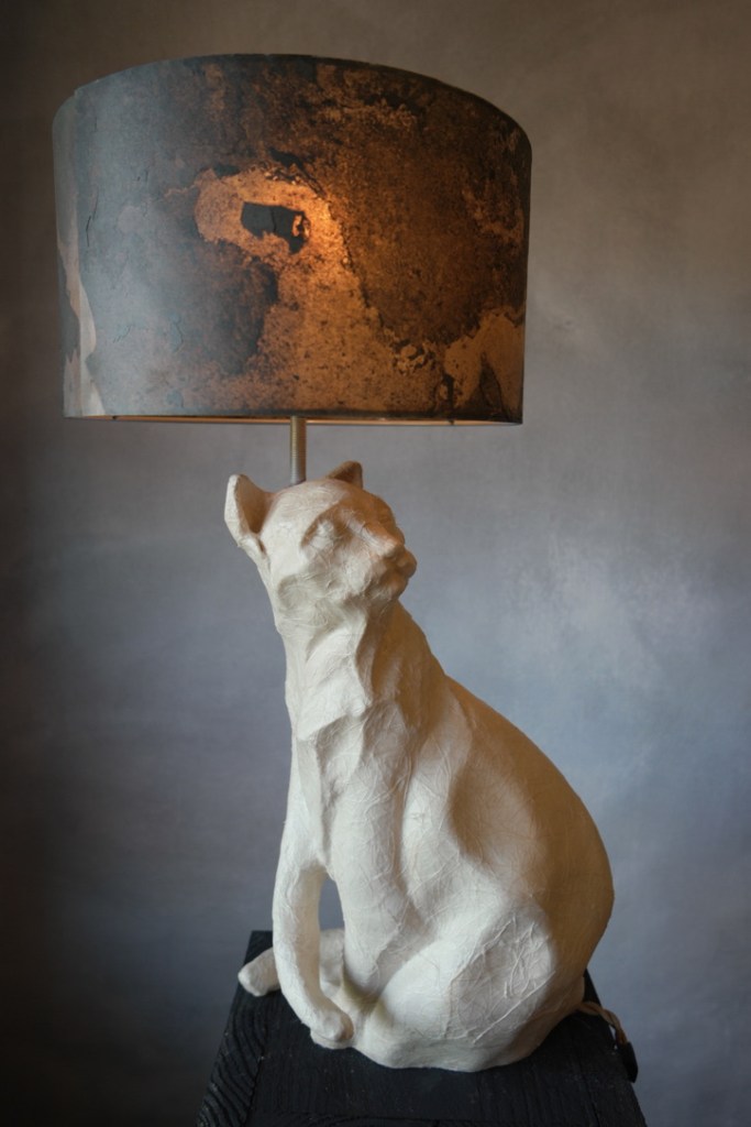 Looking back, een levensgrote witte kat lamp gemaakt van keramiek, papier, steen fineer door Jola Geldermans, vrij werk, 2023.